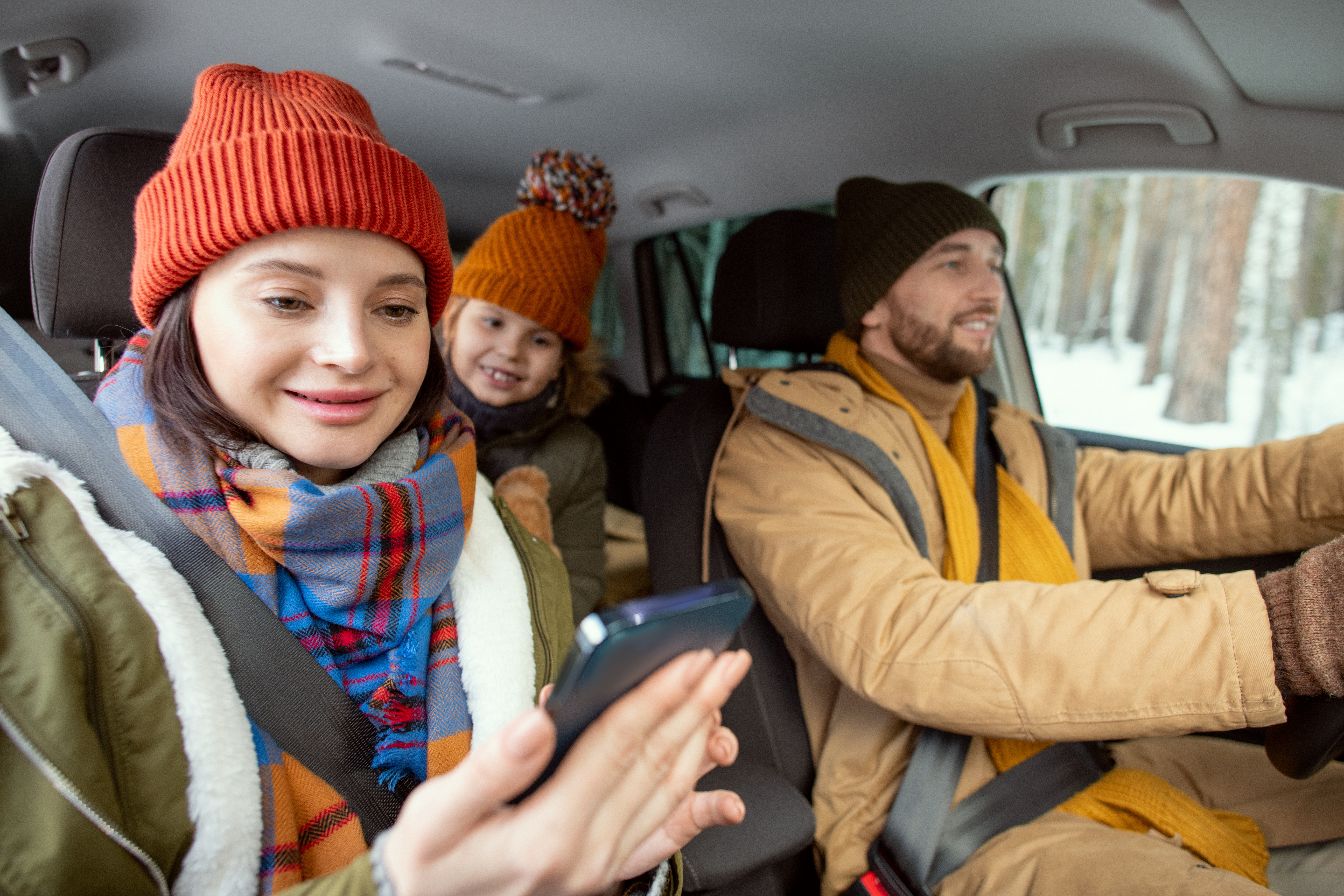 Une famille en voiture réserve ses skis en ligne avec un mobile