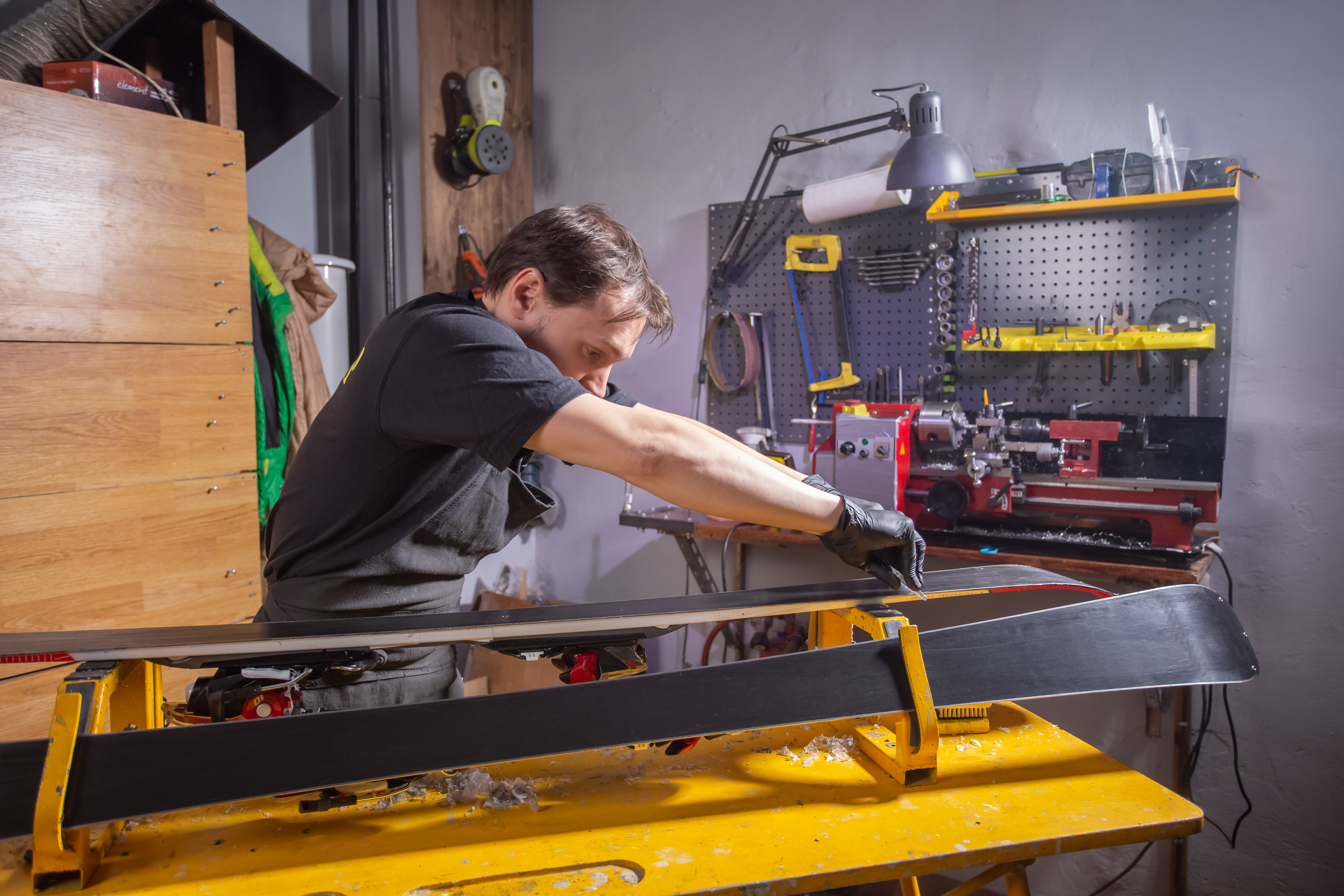 Un skiman qui farte des skis dans un atelier