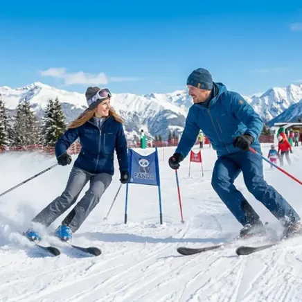 Un homme et une femme souriants skient sur une piste enneigée sous un ciel bleu, avec des montagnes et sapins en fond.