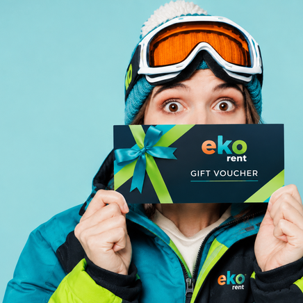 Personne en tenue de ski tenant un chèque-cadeau "eko rent", les yeux écarquillés de surprise sur un fond bleu clair.