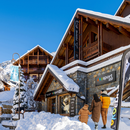 Une jeune famille devant un magasin de location de ski Ekosport-Rent